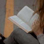 woman wearing gray long-sleeved shirt reading book