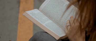 woman wearing gray long-sleeved shirt reading book