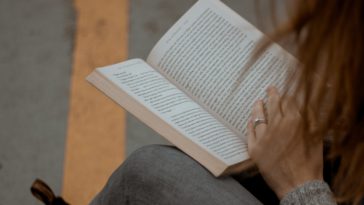 woman wearing gray long-sleeved shirt reading book