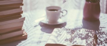 open book beside white ceramic teacup on saucer