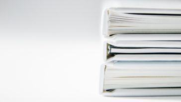 A stack of thick folders on a white surface