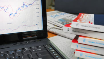 Financial books with laptop showing graphs and charts. Camera focus on graph. For concepts such as business and finance, internet and technology, and stock analysis and financial investment.